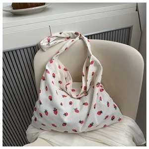 Détail du tissu en velours côtelé avec imprimés de fraises rouges sur un sac crème