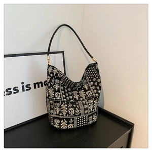 Detalle de bolso tote con estampado floral, textura de lona negra y herrajes metálicos
