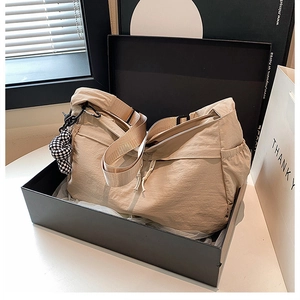 Detail van beige nylon draagtas met schaakbordbedeltje en brede verstelbare schouderriem