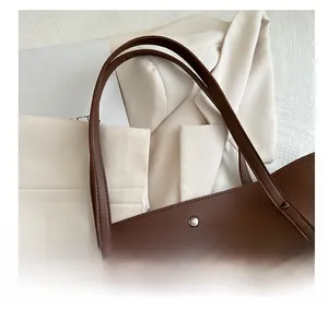 Close-up of a dark brown leather tote bag with metal rivet details and pebbled texture