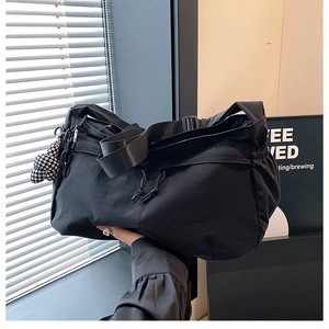 Detail van de zwarte nylon tote bag met trekkoordsluiting en geruit lintaccessoire