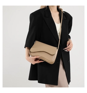 Vista lateral de mujer con bolso de cuero café y un diseño elegante de solapa ondulada