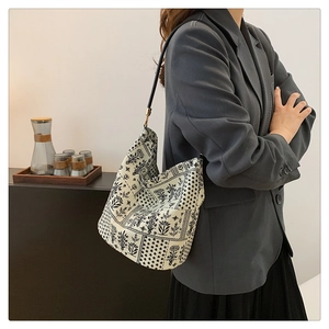 Detalle de un bolso tote elegante con estampados florales negros y herrajes dorados