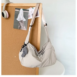 Detail van de kaki nylon draagtas met een geruit pluche hangertje op prikbord