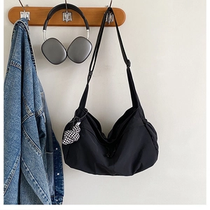 Detail van de zwarte canvas draagtas met verstelbare riem en een geruit beer-accessoire
