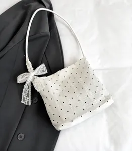Close-up of white lace bucket bag with black polka dots and delicate side bow detail
