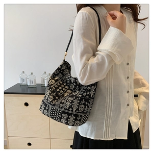 Detalle del bolso tipo cubo floral con hebillas doradas y textura de lona premium