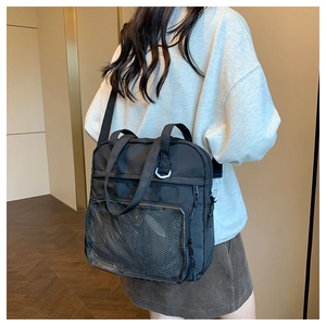 Detail view of black nylon tote bag with transparent PVC pocket shown on model
