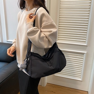 Grote zwarte canvas shopper met hartjeshanger gedragen door een vrouwelijk model