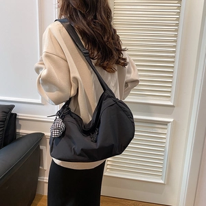 Detailweergave van een grote zwarte nylon crossbodytas gedragen door een model in casual stijl