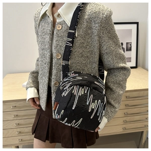 Détail du sac bandoulière noir avec broderie ondulée colorée et large sangle ajustable
