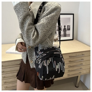 Détail du sac bandoulière en nylon noir avec zips multicouches et broderie vague