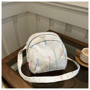 Détails de la sacoche blanche en tissu texturé avec broderies ondulées multicolores