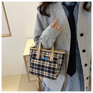 Details der karierten Eimertasche mit Cartoon-Hundestickerei und braunem Ledergriff