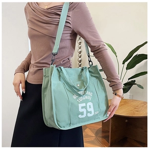 Detail of mint green canvas tote bag showing the '59' print and adjustable shoulder strap