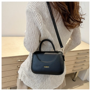 Modella che indossa una borsa a tracolla in pelle PU nera con logo FASHION e oro