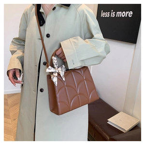 Détail du sac à bandoulière caramel avec matelassage en forme de coquille et foulard