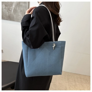 Detail of blue denim tote bag with silver metallic knot and textured fabric finish