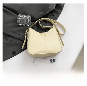 Close-up of cream crescent bag with gold 'FASHION' hardware and vertical stitching details