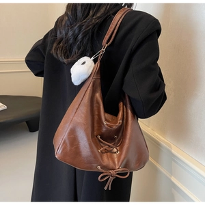 Détail du sac cabas vintage en cuir marron avec lacets et breloque en peluche