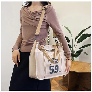 Beige canvas tote bag with retro lettering shown on a model for casual daily use