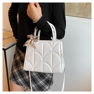 Vue détaillée du sac à main blanc matelassé avec deux poignées et un élégant foulard en soie