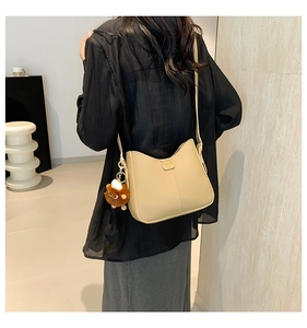 Minimalist beige moon bag with fashion logo and plush bear charm shown on model back view