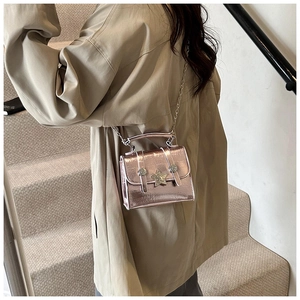 Dettaglio di una mini borsa a tracolla rosa lucida con stella d'argento su cappotto beige