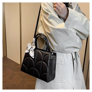 Détail d'un sac à main matelassé noir avec foulard en soie décoratif et bandoulière
