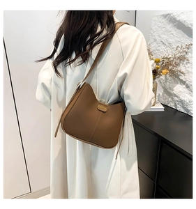 Close-up of brown matte shoulder bag with golden Fashion logo and modern curved design