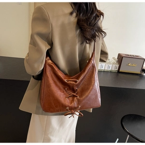 Dettaglio della borsa hobo in pelle PU marrone con lacci e occhielli in metallo su modella