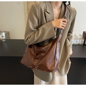 Dettaglio di una borsa tote in pelle marrone con fiocco decorativo e dettagli stringati