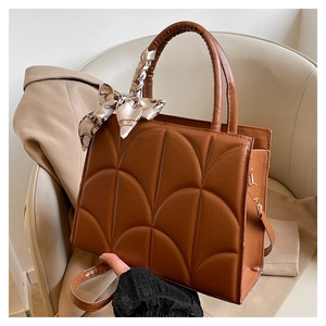 Détail du sac bandoulière caramel avec surpiqûres en éventail et poignée ornée d'un foulard