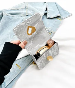 Detail of marble pattern mini bag with heart plaque holding cushion and lipstick