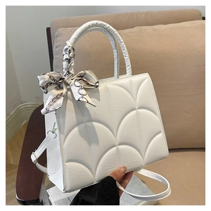 Détail d'un sac à main blanc matelassé avec un foulard en soie enroulé autour de l'anse