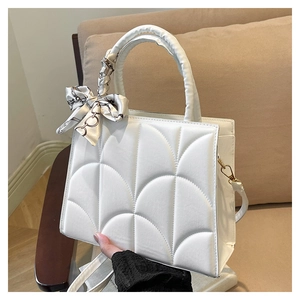 Détail du sac à main blanc texturé avec foulard en soie géométrique enroulé sur l'anse