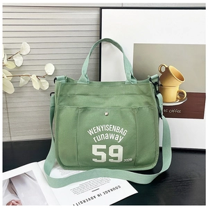 Detailed view of a green canvas tote bag with white lettering and adjustable strap
