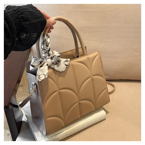 Détail d'un sac à main beige matelassé avec élégant foulard en soie sur la poignée