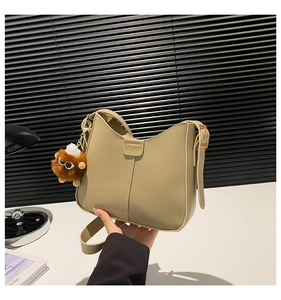 Detail of khaki PU leather bucket bag with gold Fashion buckle and plush monster charm