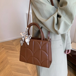 Sac à main marron en cuir matelassé avec foulard en soie, porté avec trench beige