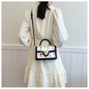 Detail van witte crossbodytas met kersenprint en bloemsluiting op wit model