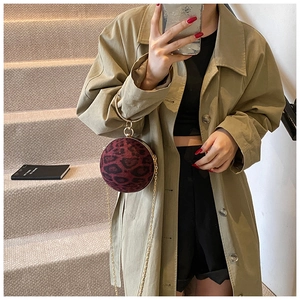 Detail of burgundy leopard print spherical handbag with gold ring handle and chain