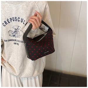 Détail du mini sac polochon noir avec motifs coeurs rouges et étiquette de marque