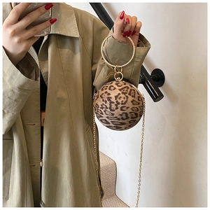 Close-up of stylish leopard print spherical bag with golden metal ring handle and chain strap