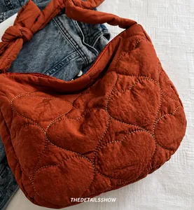 Detail shot of heart-shaped quilted tote bag in rust red with knotted strap design