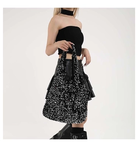 Dettaglio di paillettes argento su borsa tote nera indossata da modella in stile moderno