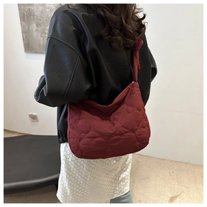 Detail view of burgundy quilted heart pattern on soft padded nylon shoulder bag