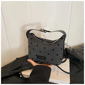 Détail du sac polochon en tricot gris foncé avec pois noirs et logo de marque