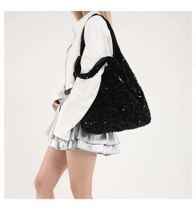 Dettaglio delle paillettes nere lucide e del design capiente della borsa a tracolla