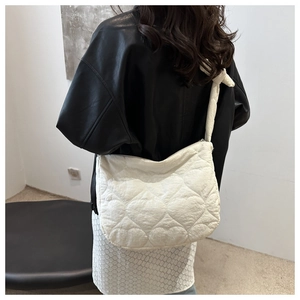 Close-up of white heart-quilted tote bag featuring soft texture and knot shoulder strap